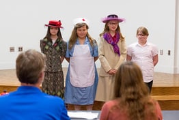 Four students dressed in costume in front of a stage.